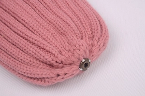 Close-up of pink knit fabric showing detailed texture and metal eyelet attachment