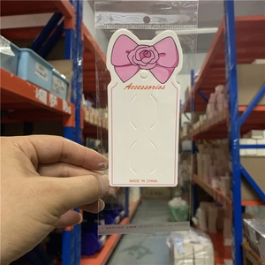 Close-up of pink bow jewelry display card inside clear adhesive packaging bag