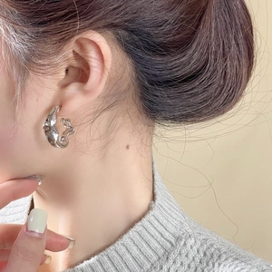Close-up view of irregular metallic hoop earrings showcasing modern fluid silver design and details.