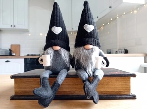 Close-up of handmade Christmas gnomes with knit hats sitting on books in a cozy kitchen