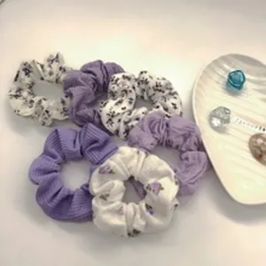 Dettaglio di elastici scrunchies viola in maglia e floreali con piatto decorativo