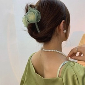 Dettaglio di un fermaglio per capelli a forma di fiore in tulle verde chiaro su modella