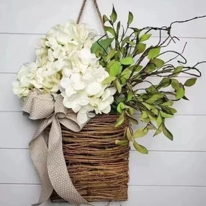 Hanging basket with white hydrangeas and green leaves on a white shiplap wall background