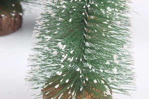 Detailed close-up of mini artificial pine Christmas tree with white snow effect and wood base