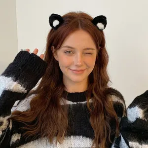 Charming black plush cat ear headband with white inner lining worn by a smiling woman