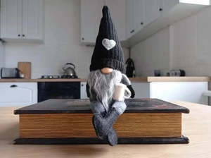 Knitted faceless gnome doll with coffee theme sitting on vintage books for home decor