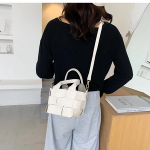 Detail view of cream woven shoulder bag on model with modern minimalist style