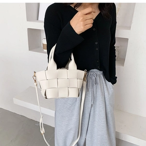 Detailed shot of white woven crossbody bucket bag shown with model for size reference