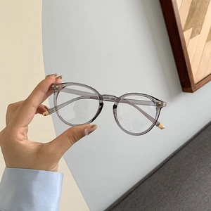 Detailaufnahme einer transparent grauen runden Brille mit metallischen Bügelakzenten