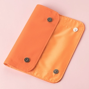 Detail of orange faux leather makeup brush storage bag with magnetic snap closure