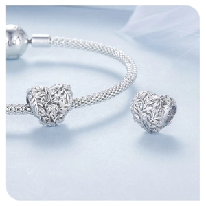 Macro shot of S925 sterling silver heart charm with leaf patterns and zircon on mesh bracelet