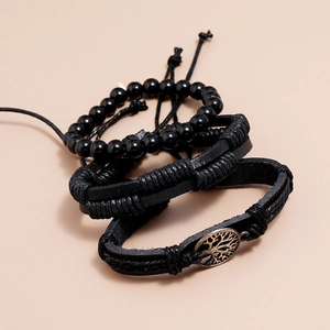 Detailed macro view of vintage black leather bracelets with bronze tree of life charm