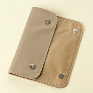 Detailed top view of beige faux leather jewelry roll with dual metal magnetic buckles