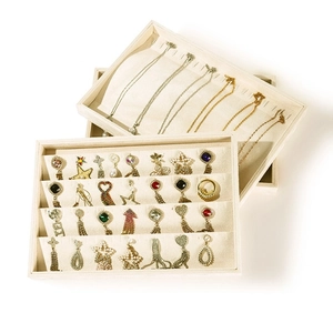 Beige velvet jewelry organizer trays for necklaces and earrings in a stacked display