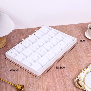 Macro view of white jewelry display tray with dividers on a wooden desk setting