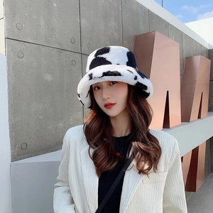 Stylish cow print plush bucket hat worn by a model in a modern outdoor setting