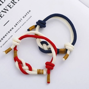 Macro detail of red and blue braided nautical bracelets with golden thread accents