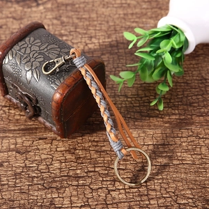 Detail of handcrafted gray woven leather keychain with vintage bronze metal spring clasp
