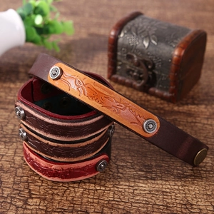 Detail of vintage braided leather bracelets with metal snaps on a rustic wood background