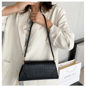 Close-up of black crocodile embossed shoulder bag worn by model for daily wear