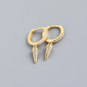 Close-up of gold geometric cone drop earrings with sparkling pavé zircons on gray background
