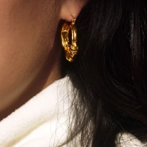 Close-up of elegant gold S925 sterling silver knot earrings worn by a model