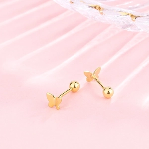 Macro detail of gold butterfly S925 silver screw back stud earrings on pink texture