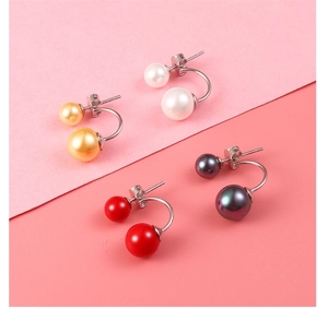Detailed view of dual-pearl stud earrings in four colors on a pink backdrop