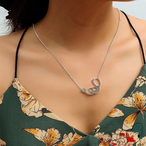 Detail of stethoscope heart pendant necklace with heartbeat line on a female wearer