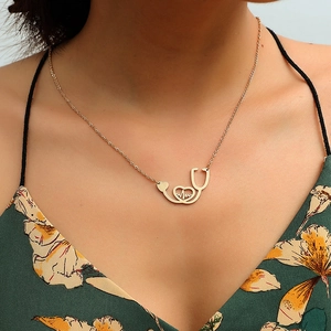 Golden stethoscope heart necklace with EKG line shown on model in floral dress