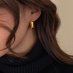 Close-up of elegant polished gold irregular earrings on a model with mirror finish