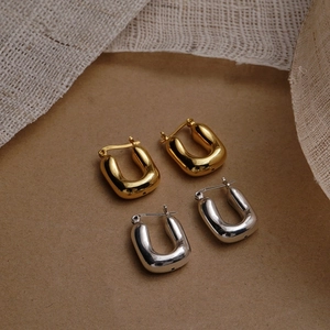 Macro shot of U-shaped gold and silver earrings showing the S925 sterling silver stamp