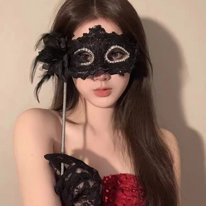 Detail of elegant black lace masquerade mask with feathers and matching gloves