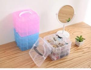 Detail view of 3-tier stackable jewelry organizers in pink, blue, and clear with handle
