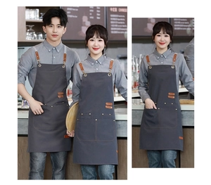 Detail of grey canvas apron with brown leather straps and metal buckles for baristas