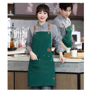 Detail of green canvas apron with brown leather straps and multi-pocket design in a cafe