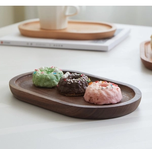 Detail van ovaal notenhouten dienblad met mini donuts op een witte tafel