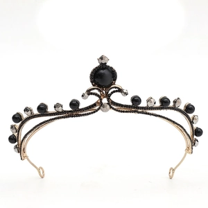 Detail of baroque crown featuring black beads and antique gold metal frame on white backdrop