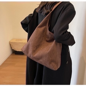 Brown faux suede tote bag shown on shoulder in a minimalist lifestyle setting