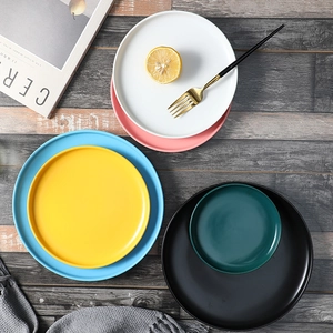 Nordic matte ceramic plates in various colors and sizes displayed on a wooden table