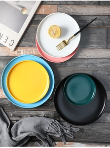 Flat lay of Nordic matte ceramic plates in multiple colors on a vintage wood surface
