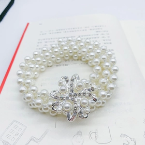 Detail of multi-layer pearl waist chain featuring a sparkling rhinestone flower buckle