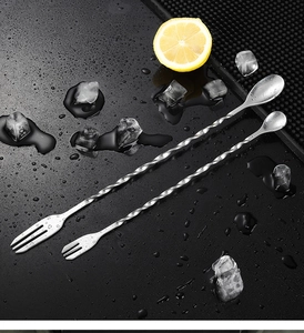 Dual-purpose cocktail bar spoon with spiral handle on ice with lemon slices