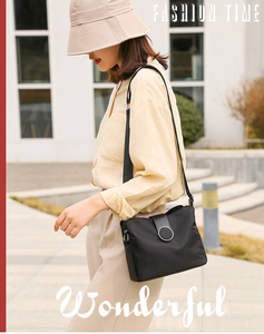 Detail shot of black nylon crossbody bag with round metal buckle and wide strap