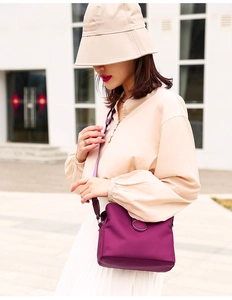 Detail view of purple nylon crossbody bag with metal ring shown on a model outdoors