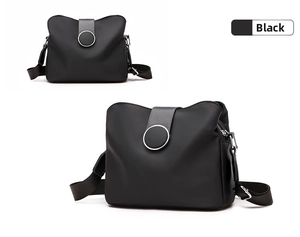 Detail of black nylon crossbody bag with round decorative buckle and metal zippers
