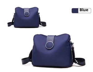 Detail view of deep blue nylon crossbody bag with circular metal hardware and adjustable strap