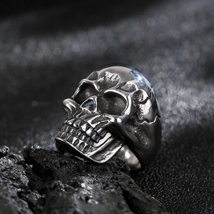 Macro shot of vintage titanium steel skull ring on a black rock base with gothic details