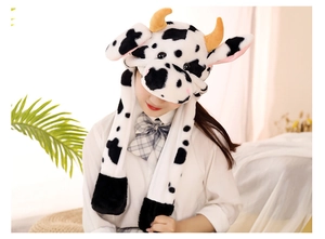 Plush cow print hood with ear flaps and long ties worn by a model in warm light