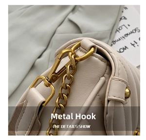 Detail of premium gold metal hooks and quilted leather texture on a white handbag